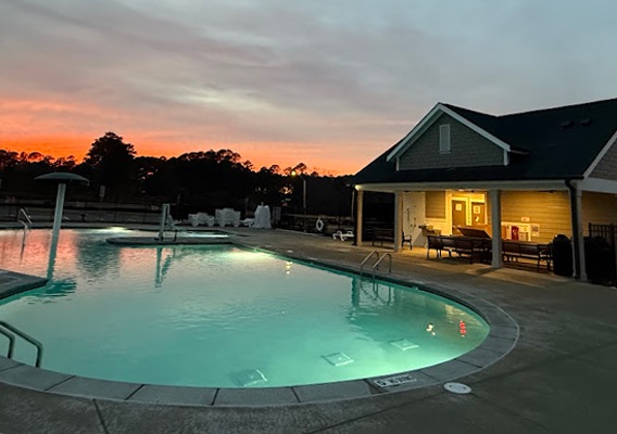 Outdoor pool area with exterior lighting installation at sunset